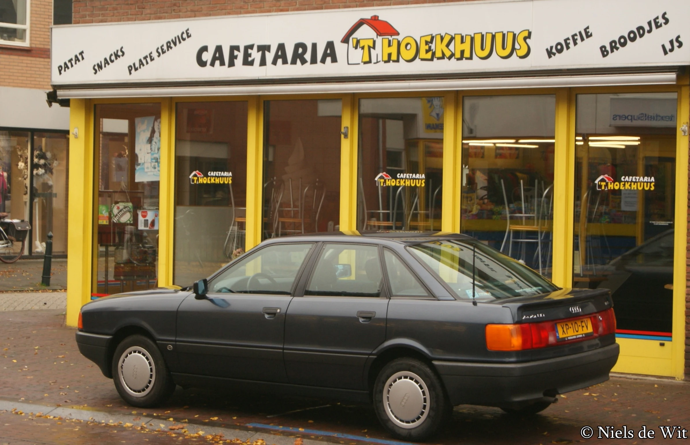 a black car parked in front of a restaurant