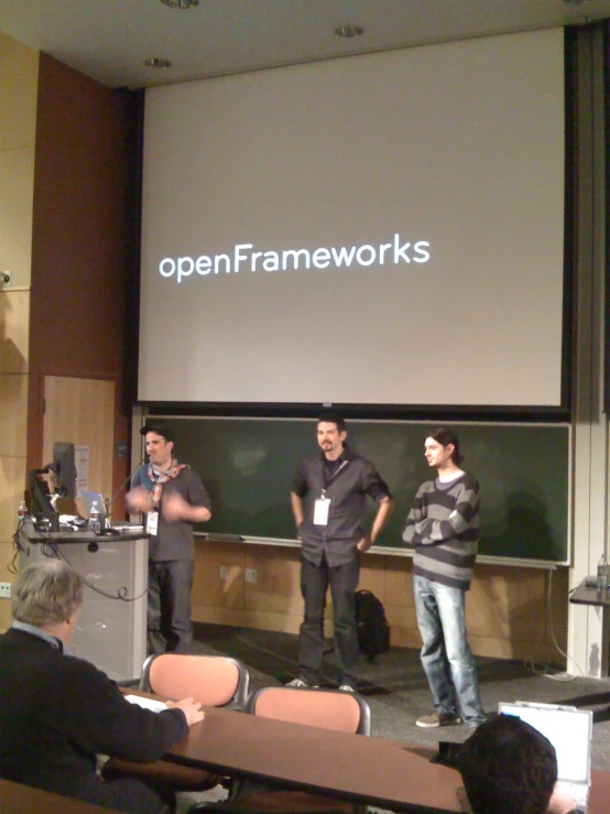 four men standing in front of an audience during a presentation