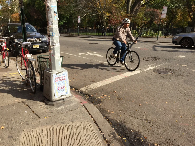 person on bike stopped at light pole next to street