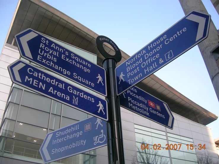 blue street signs in front of a modern building