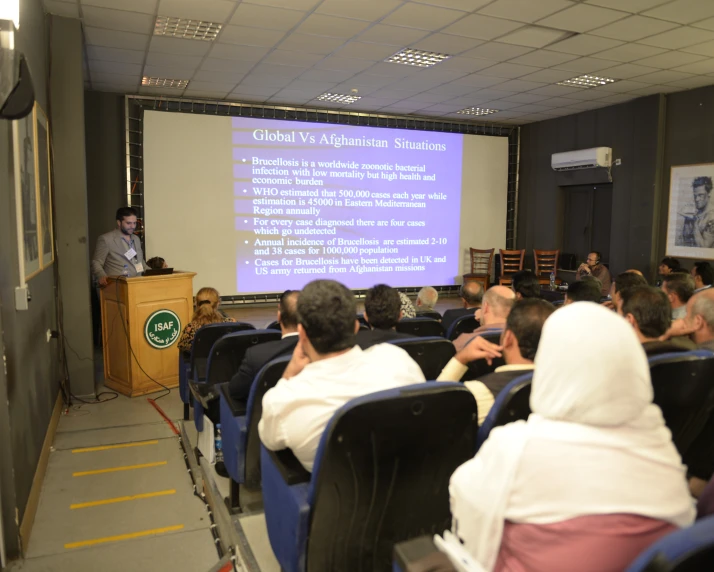 an audience listening to speakers in front of a powerpoint slide