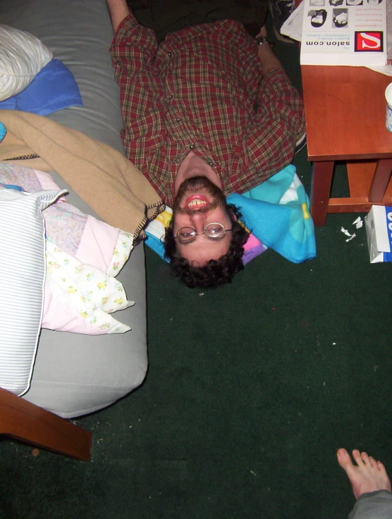 a man is laying on the floor near a blanket and pillows