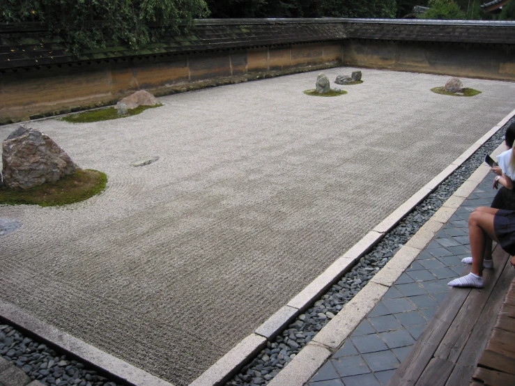 a person taking a picture with his phone near a stone garden