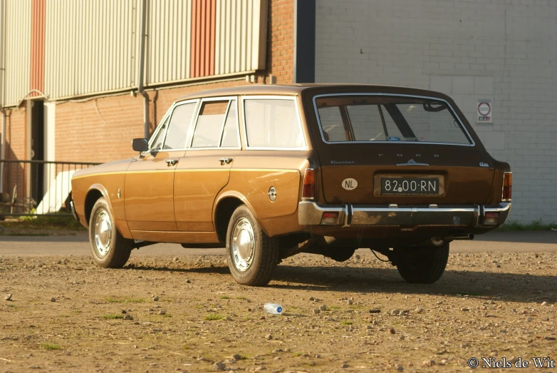 a rusted out brown car sitting on the side of a road