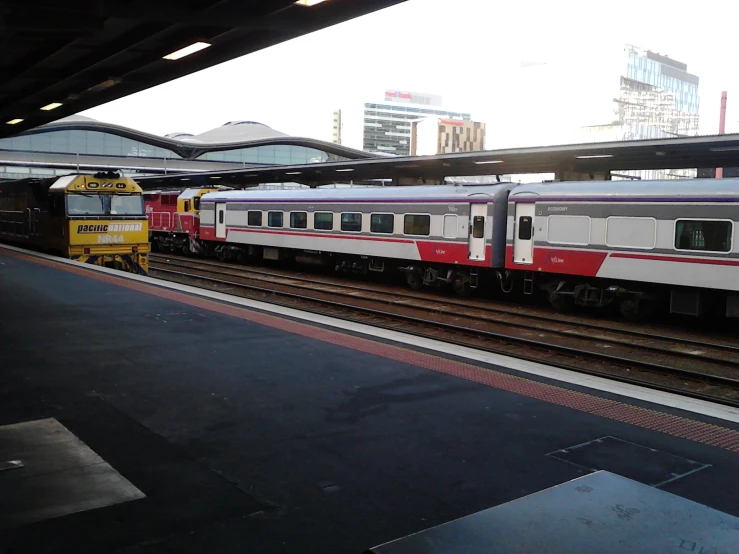 two trains in a train station with buildings in the background