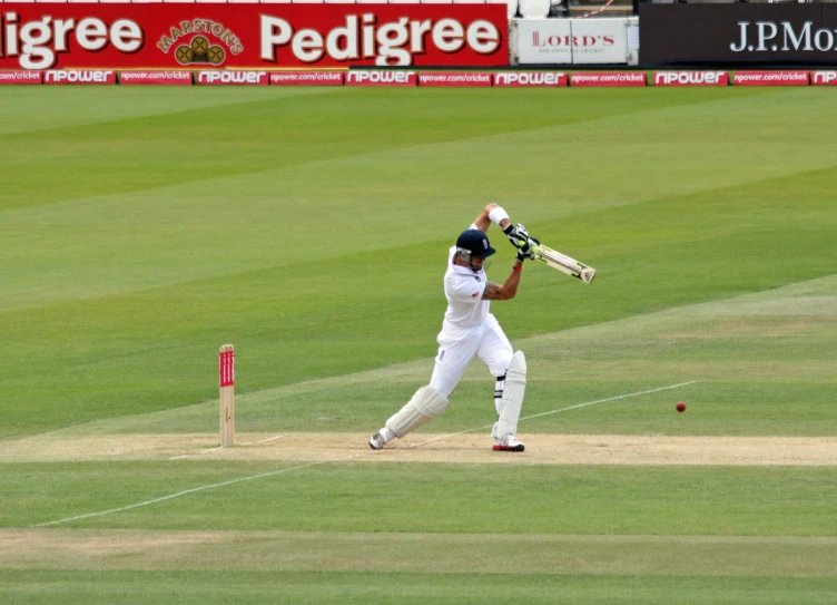 a player in a white uniform hitting a ball with a bat