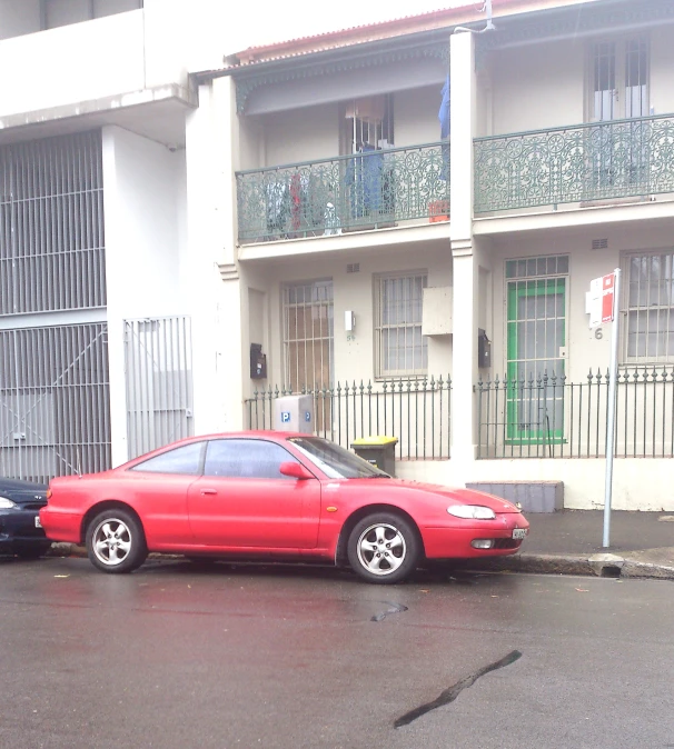 a red car parked in front of a white building