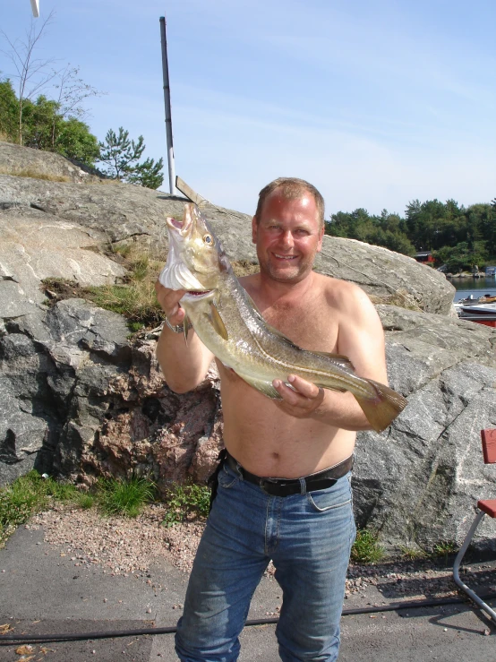a man holding a large fish and a rod