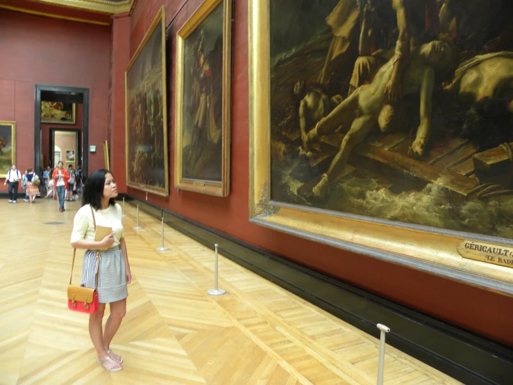 the girl stands in front of a museum with art on display