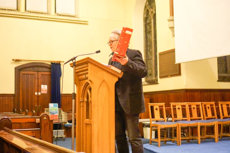 a man is standing at a podium with a red package on his head