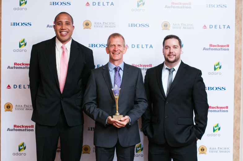 three men posing for a picture while wearing suits