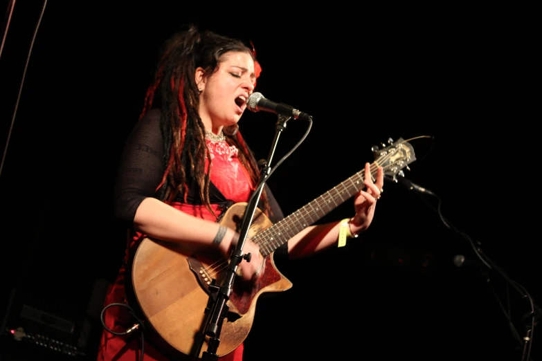 a young woman singing and playing a guitar