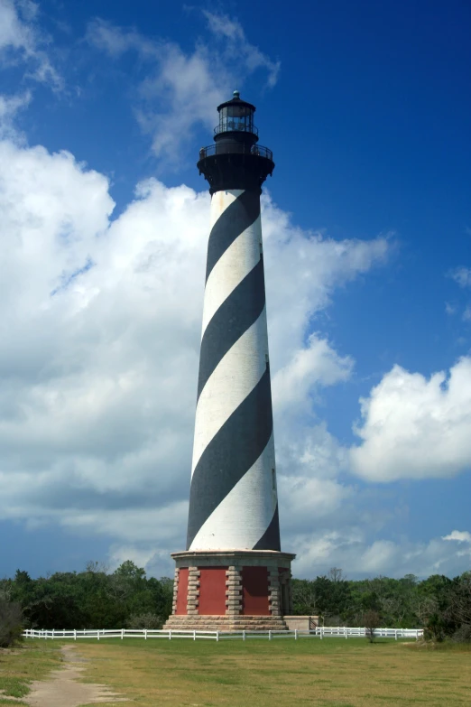 a large black and white light house near a lush green field