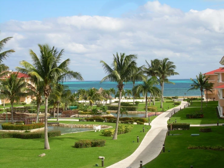 an open walkway leads to a lush green lawn area on the beach