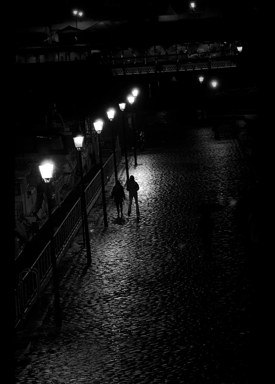 a man standing under an umbrella on a rain soaked walkway