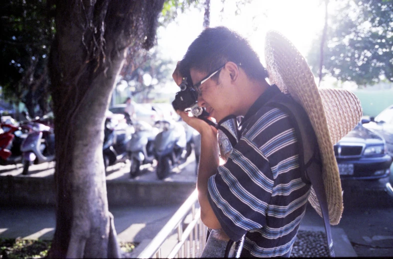 a man holding a camera looking at it in the street