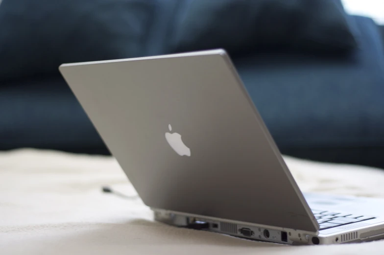 a laptop computer sits on a bed in the sun