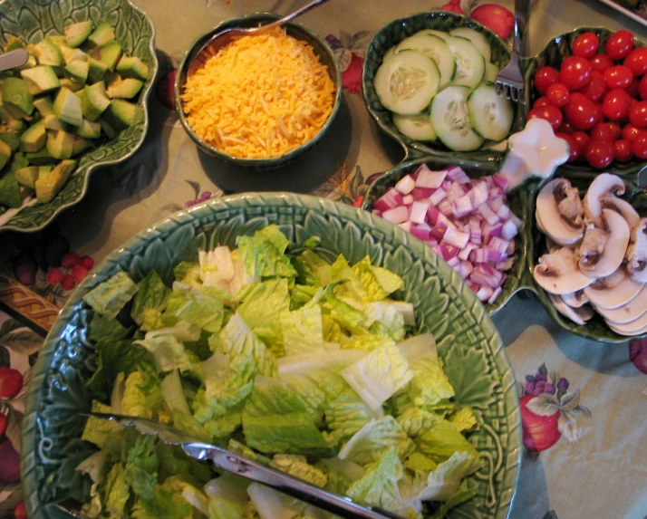 bowls of vegetables such as cucumbers, peppers and salad dressing are part of a food display