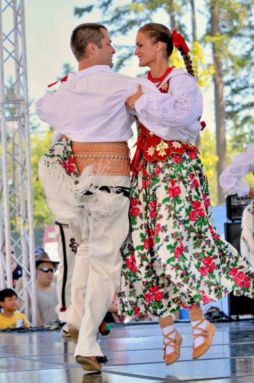 a man and woman are dancing in a folk costume