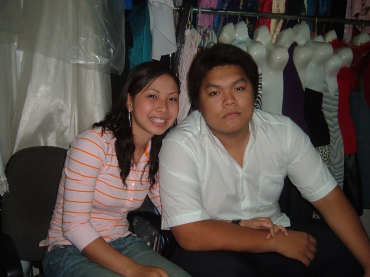 a man and woman posing for a po in front of their clothing