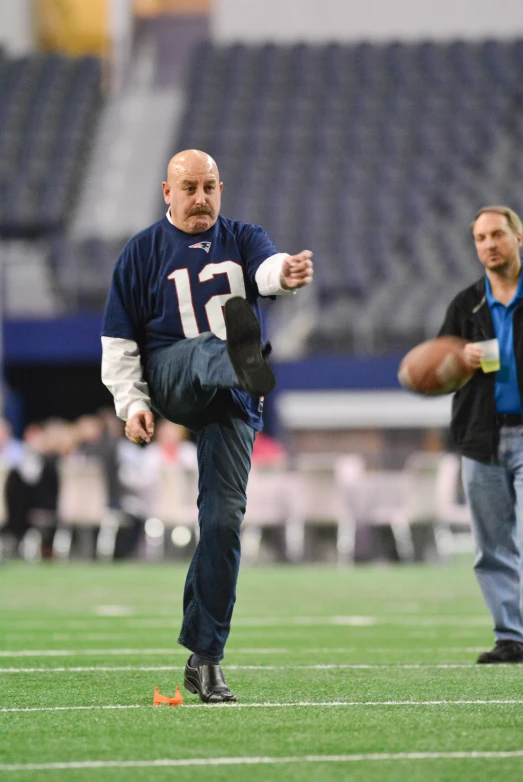 an old man with a football standing on the field