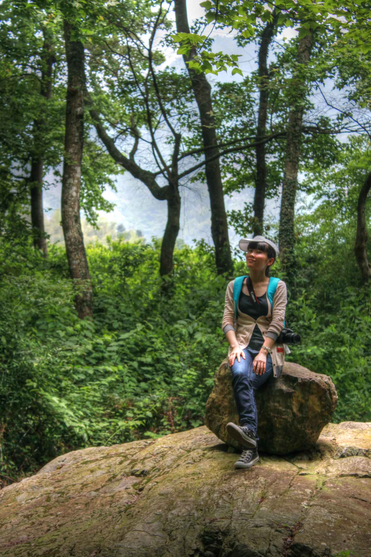 man with hiking backpack sitting on large rock in forest