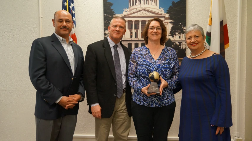 two men and two women pose for the camera with an award