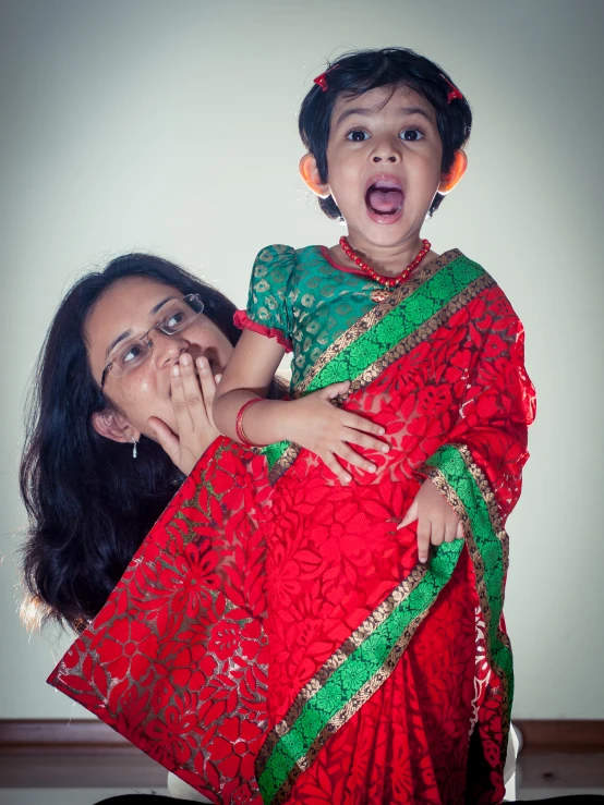 a woman in red sari holding a small child