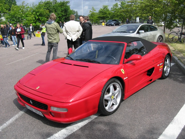 people standing around and a ferrari sports car on a parking lot