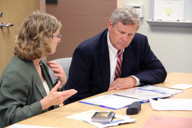 a man and woman are sitting at a table with papers