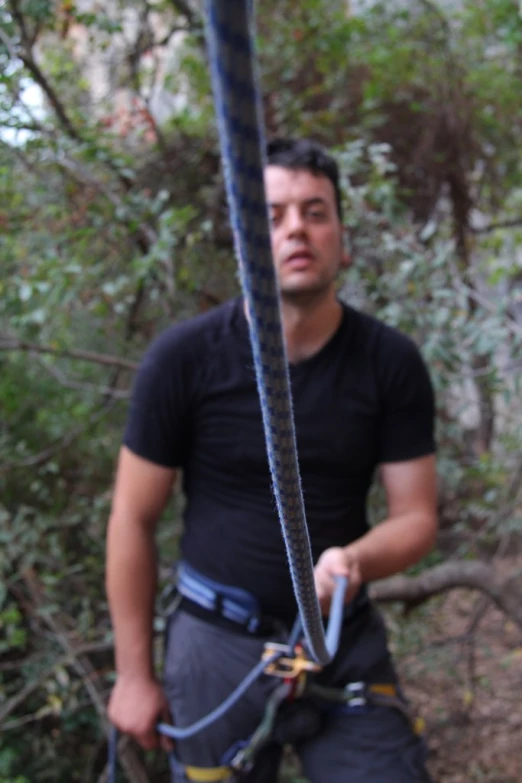 a man standing in the forest holding a rope