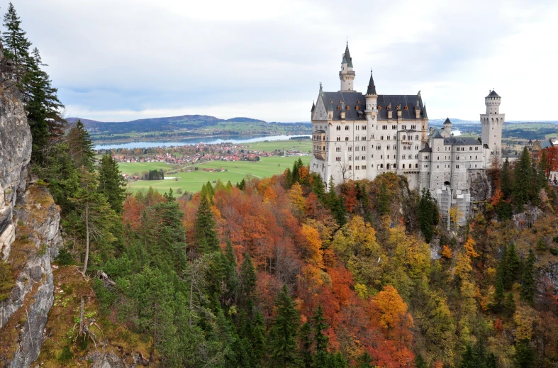 an impressive castle is surrounded by fall colored trees