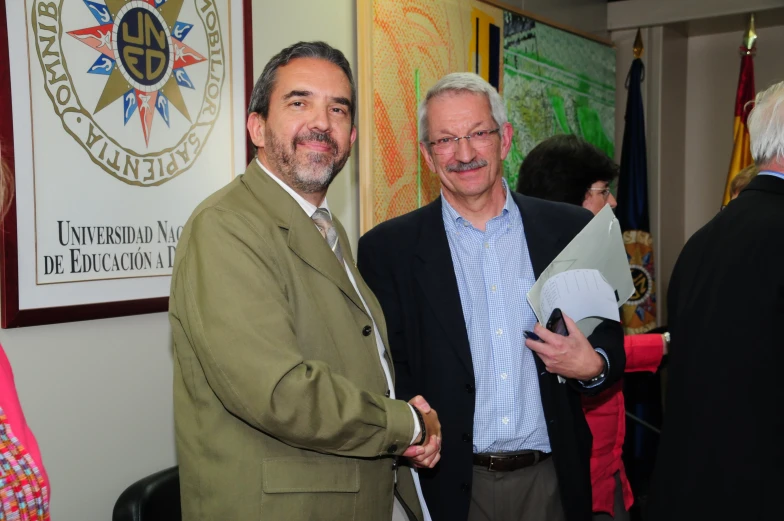 two men in suit suits holding papers standing together