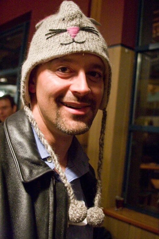 a man smiling wearing a hat with a cat face