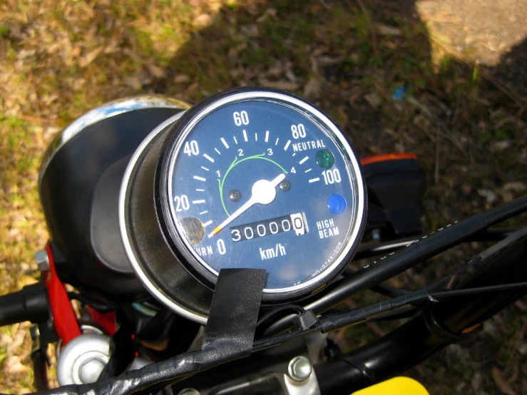 a clock is on the handlebars of a motor bike