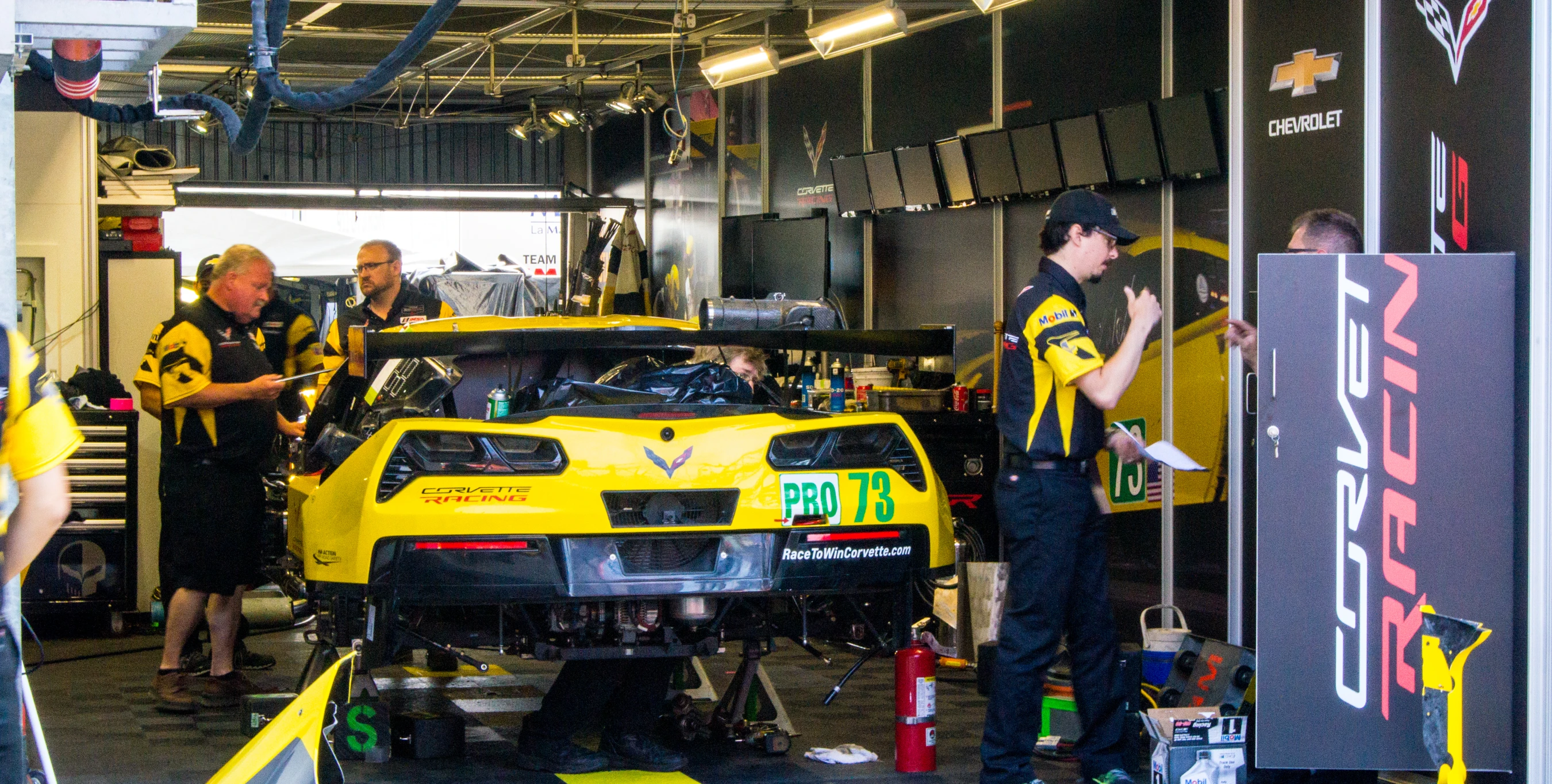 two yellow car mechanics working on their cars