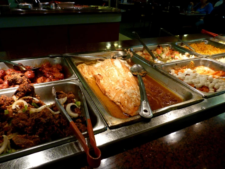 an image of buffet line filled with meats and sides