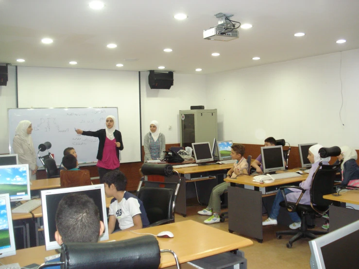 a group of people sitting at desk in front of computers