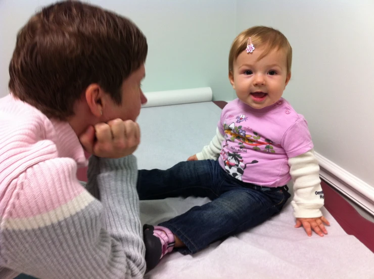 a small child sits on the floor with its mom