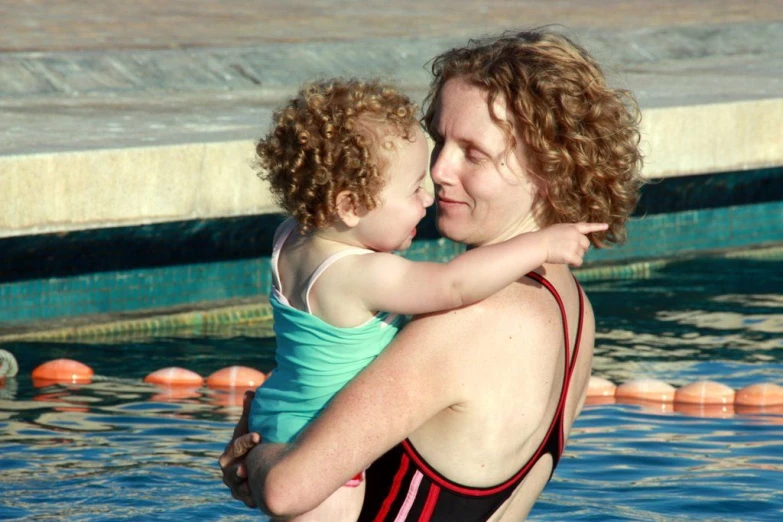 a person holding a child in a swimming pool