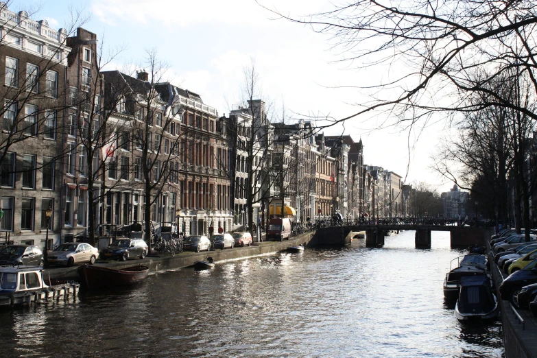 canal in middle of building with bridge, boat and tree nches