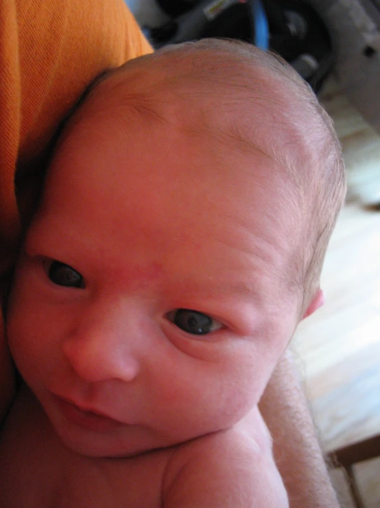 a close up of a baby holding onto an orange pillow