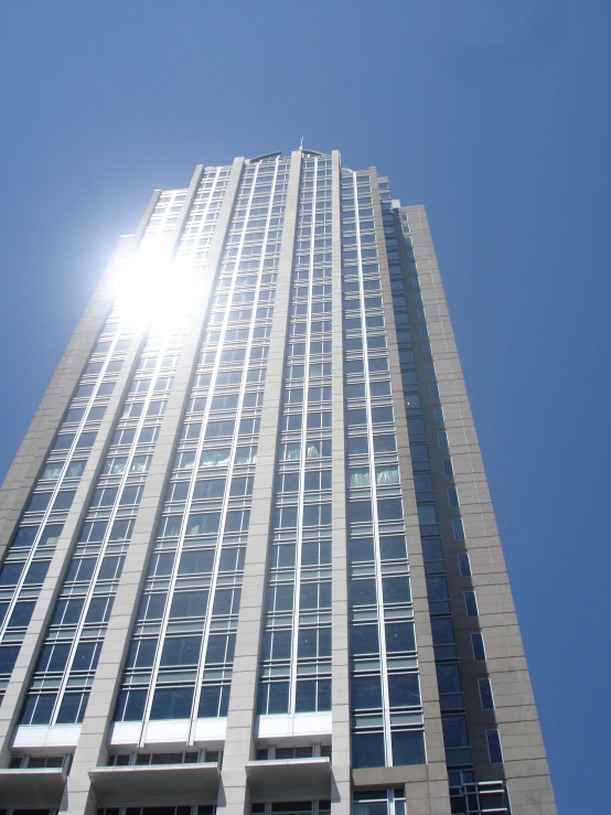 the sun shining on a tall building with many windows