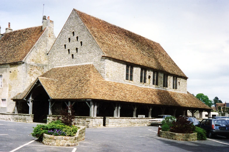 a large house with a thatched roof next to parked cars