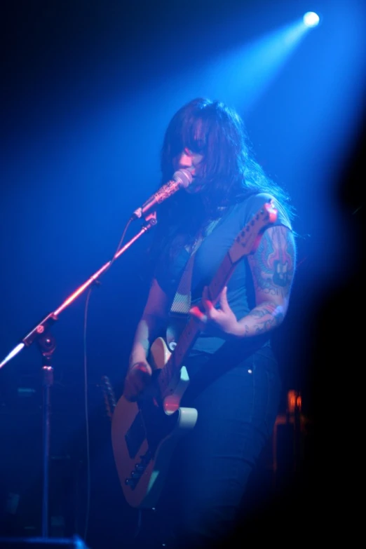 a woman with long hair playing a guitar on stage