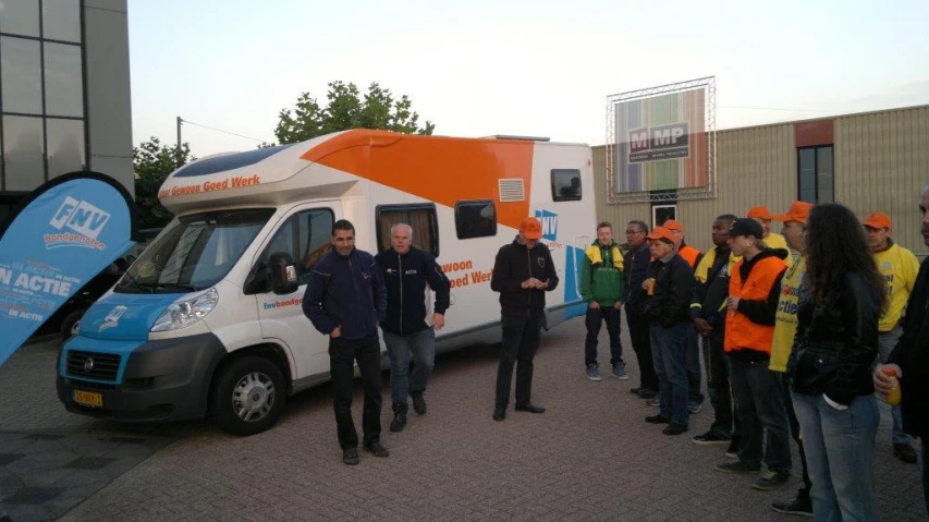 some men are standing outside of a small van