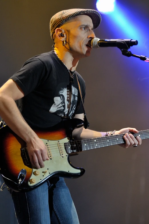 a guy playing guitar while standing on stage