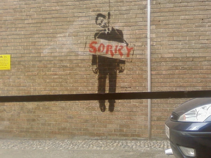 graffiti on the side of a building, depicts a man holding a sign