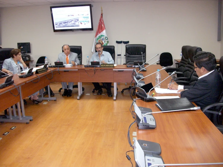 a group of people sitting around a wooden conference table