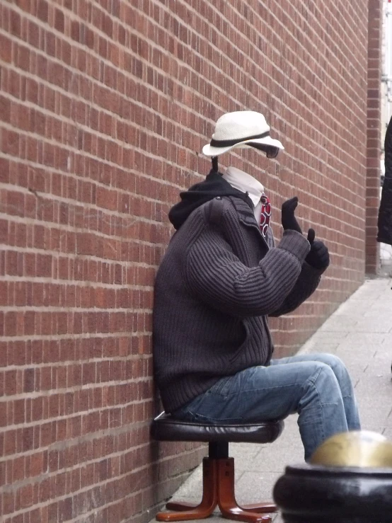 an odd man is sitting in front of a brick wall